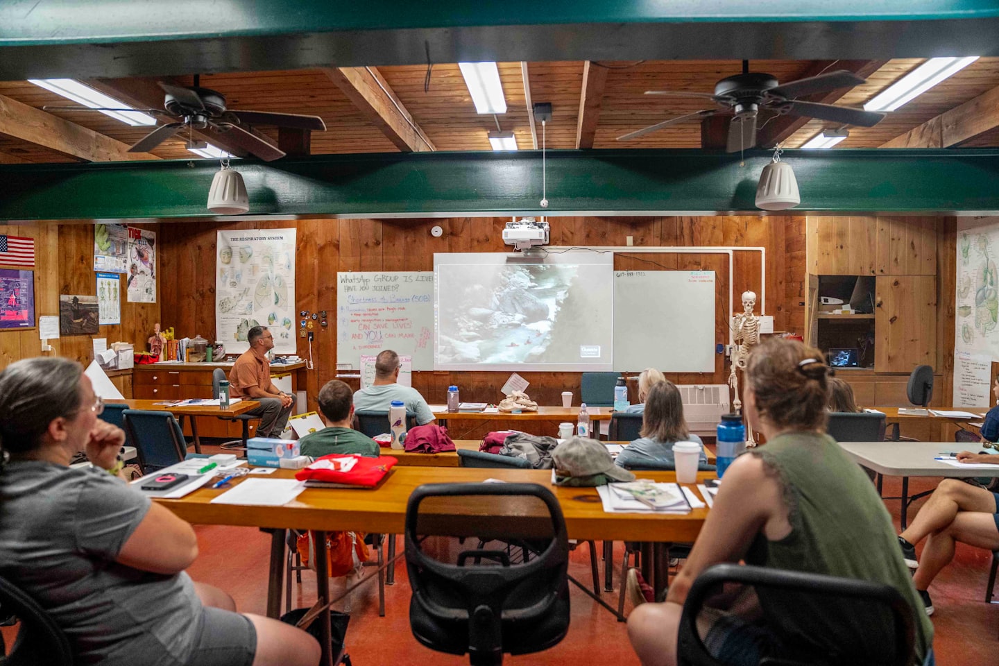 Instructor leads diverse adults in indoor training session with projector.