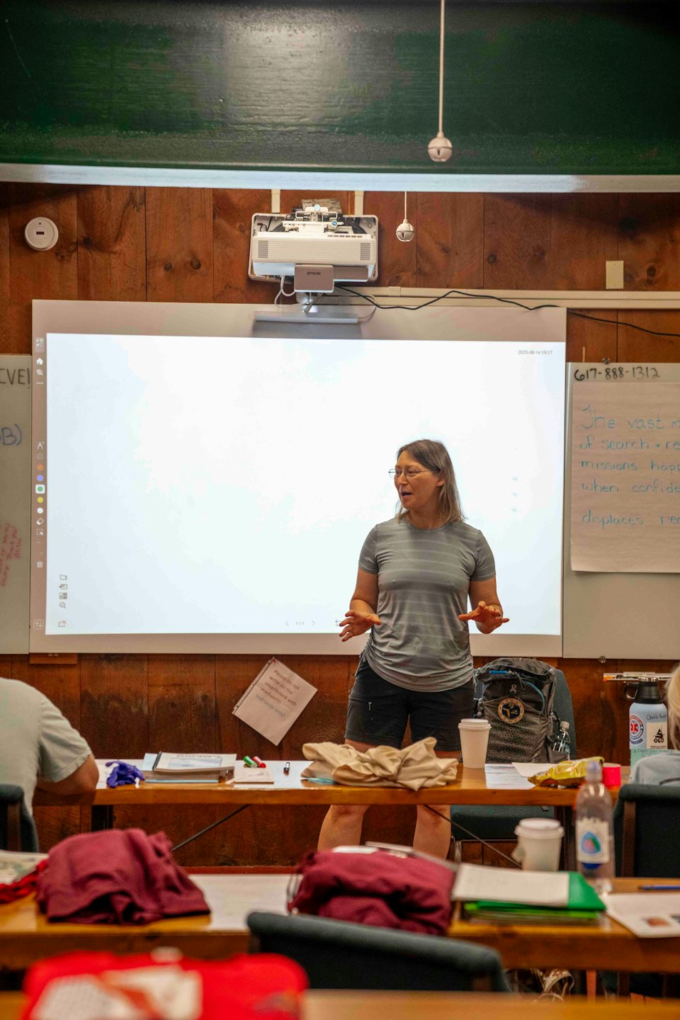 Woman presents interactively at a large display in a classroom.